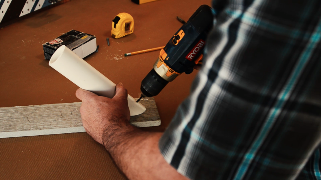 Predrill a hole in the PVC pipe to mark where it will be attached to the board.